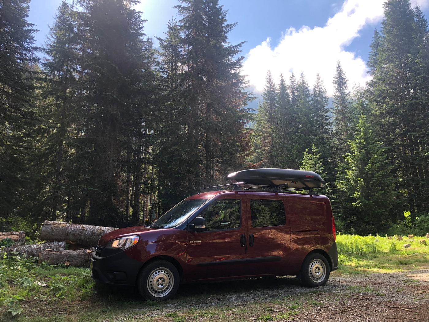 Red Ram ProMaster City RV rental van, equipped with a roof cargo box, rests in a sun-dappled forest. — photo 14