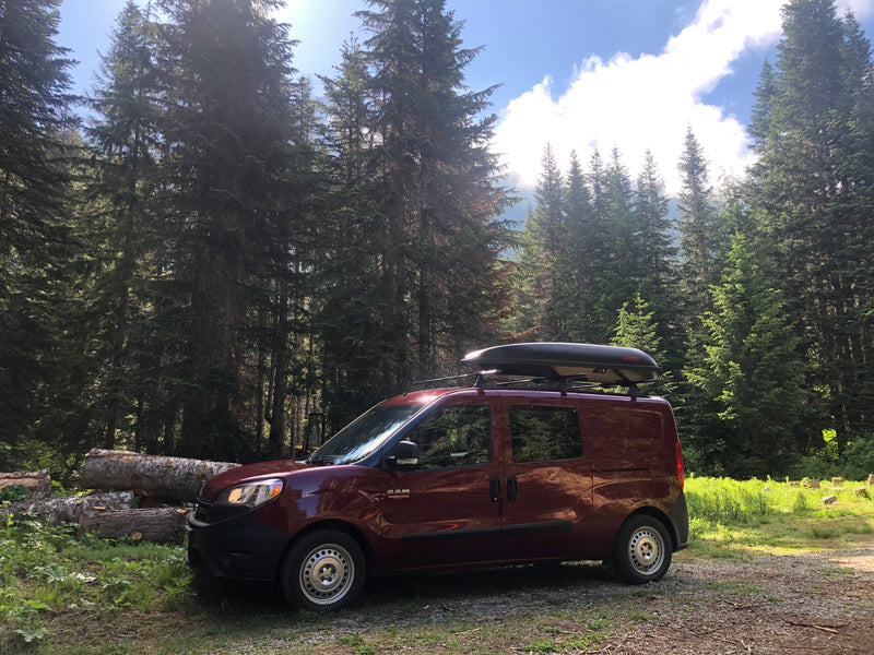 Red Ram ProMaster City RV rental van, equipped with a roof cargo box, rests in a sun-dappled forest. — photo 14