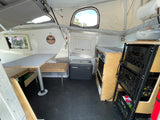 This RV rental's interior reveals a pop-top design, offering a versatile dinette, Dometic fridge, and compact kitchen.