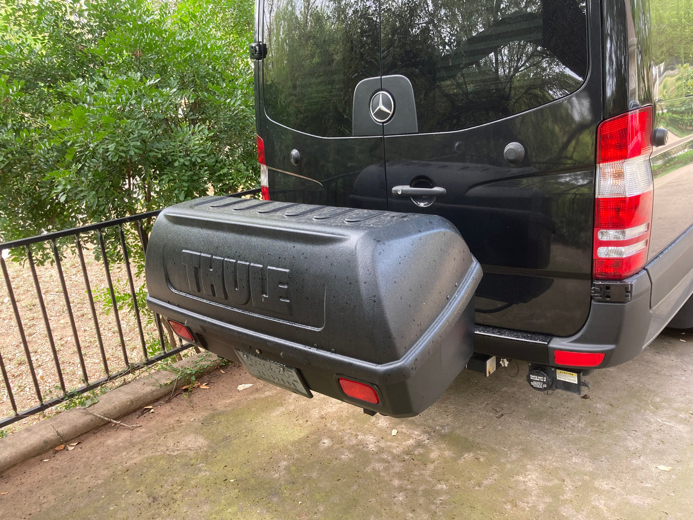 Rear of a black Mercedes-Benz Sprinter RV rental, with a Thule cargo box for extra gear.