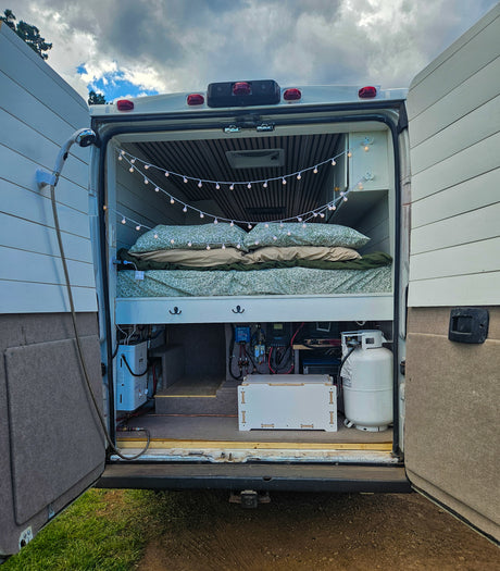 RV rental van interior showcasing a cozy bed, outdoor shower, essential power systems, and propane for your adventures.