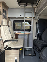 Cozy RV rental interior: dinette with table, seats, ladder to bed, and control panel visible.