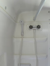 Compact white shower in an RV rental, with a hand-held shower head, faucet controls, and a grab bar.