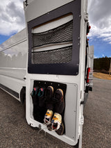 Open rear door of an rv rental showcasing clever storage: mesh nets for gear and a multi-pocket shoe organizer for footwear.