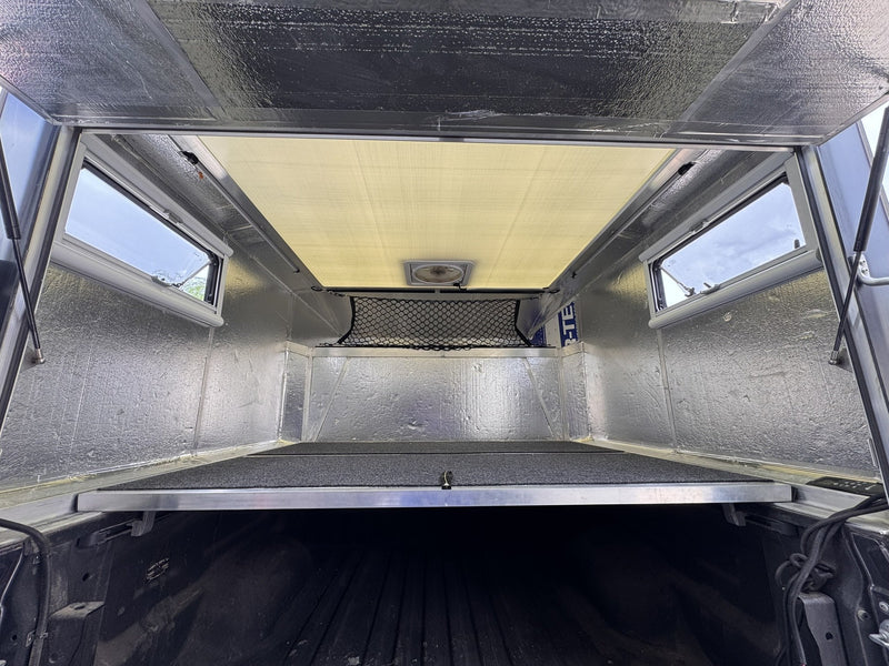 Interior of the Moonlander X showing the carpeted lofted bed platform, insulated walls and roof fan — photo 7
