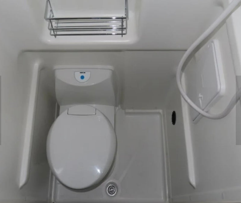 Compact white RV rental bathroom with a toilet, shower hose, and chrome shelf, ready for your trip. — photo 1