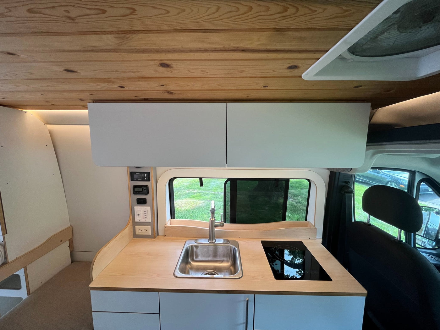  surrounded by greenery.|White "Dave & Matt Vans" RV rental parked on a driveway with trees. Features a window & Dometic unit on the roof.|Modern silver camper van for rv rental. Open doors reveal a custom interior with kitchen — photo 5