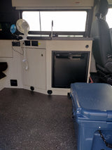 Inside this rv rental, a compact kitchen features a sink, refrigerator, and handy fans. A large cooler sits on the floor.