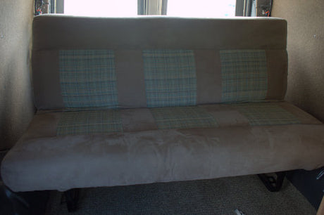 RV rental: Beige upholstered bench seat with three blue plaid sections, likely in a camper van interior.