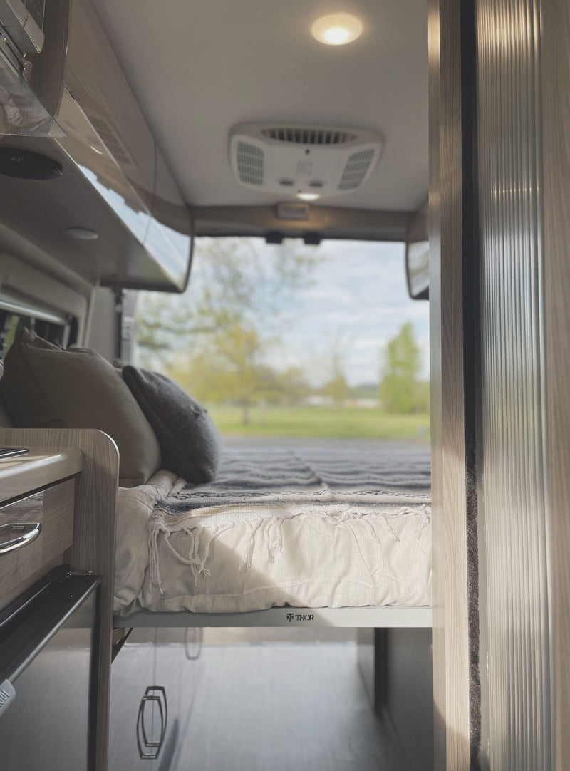  next to a camper van and melting snow in a forest.|Driving an RV rental on a scenic road trip. Interior view showing steering wheel & mountain views.|Interior of a modern RV rental — photo 7