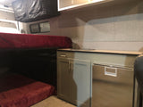 Inside an RV rental: features include bunk beds, a compact kitchenette with a fridge, and overhead storage.