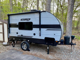 Sun Lite Sport travel trailer (RV) parked on gravel by trees. Perfect for an RV rental camping trip.