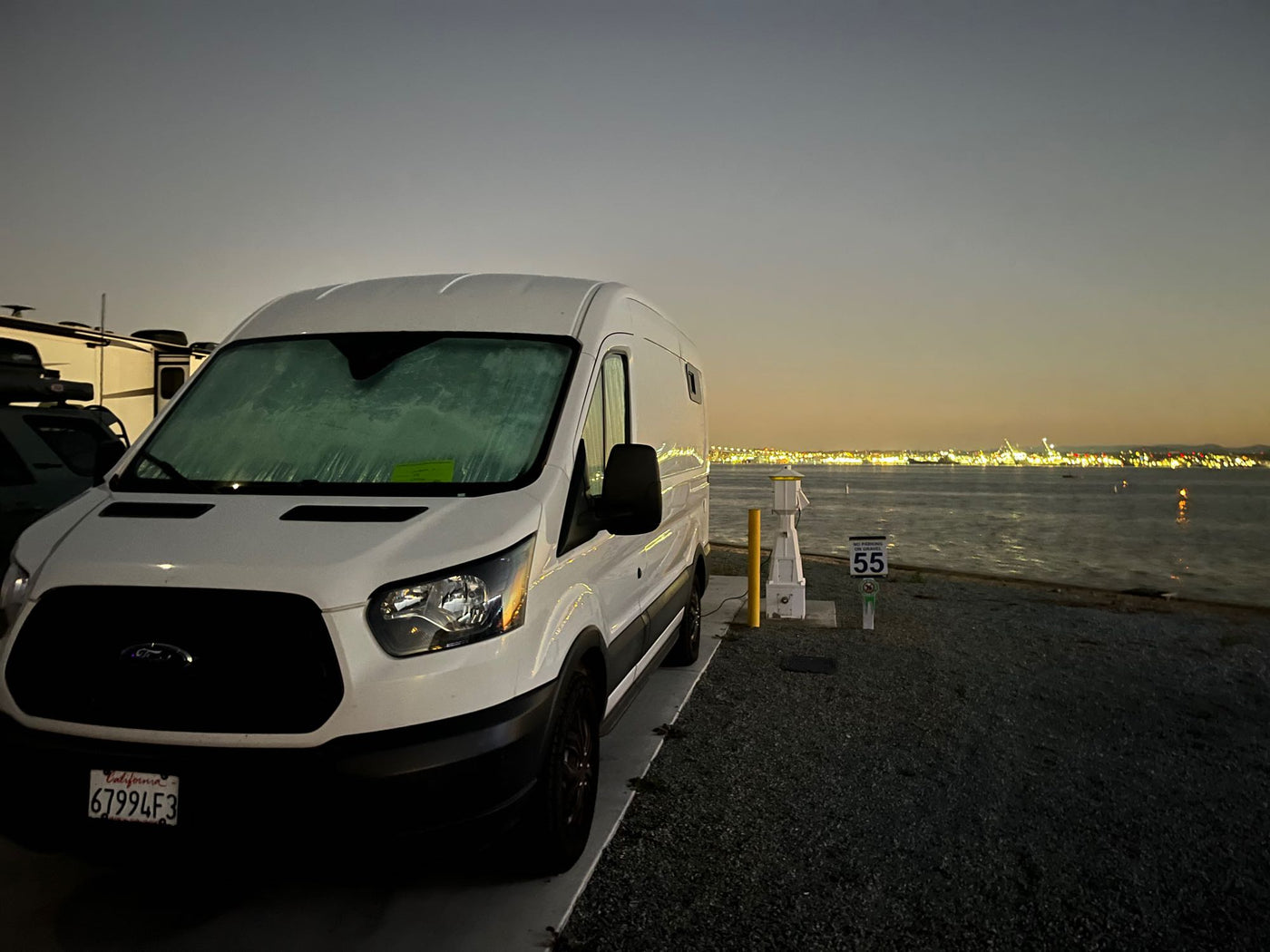  cloudy sky.|White Ford Transit RV rental parked at sunset. This camper van has a flat front tire — photo 7