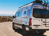 White Winnebago Revel 4x4 Sprinter RV rental on a dirt road. This off-road camper van is ready for scenic mountain adventures.