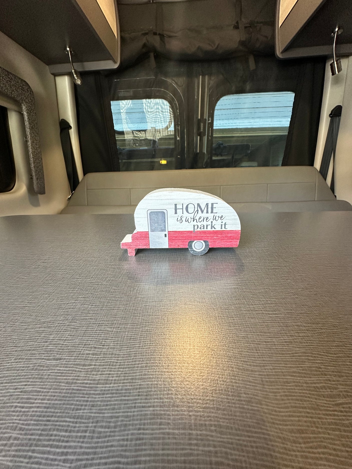 Cozy RV rental interior featuring a "HOME is where we park it" camper decoration on a comfortable bed or seating area.