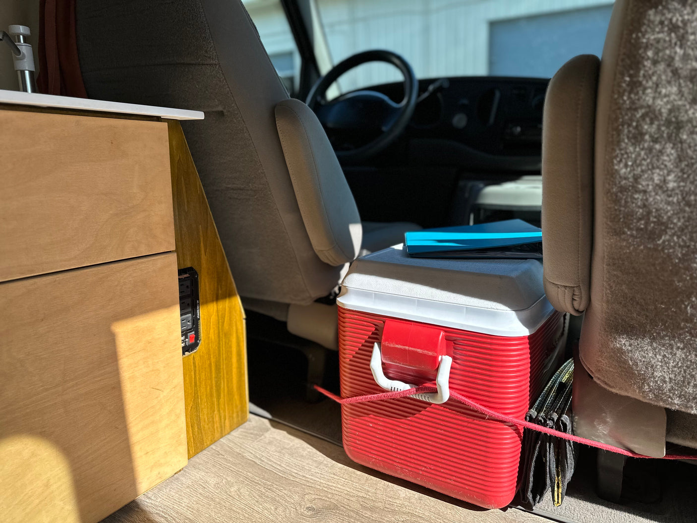 RV rental: Efficient interior with a red cooler, built-in storage, and power outlets for your next adventure.