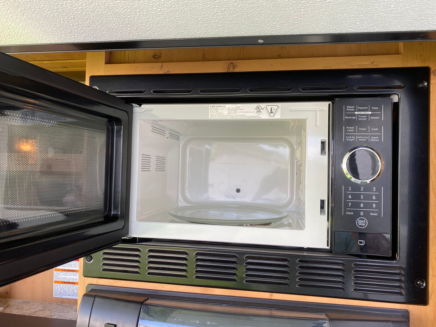Open microwave oven in an RV rental kitchen, ready for use. Features a visible control panel and interior glass plate.