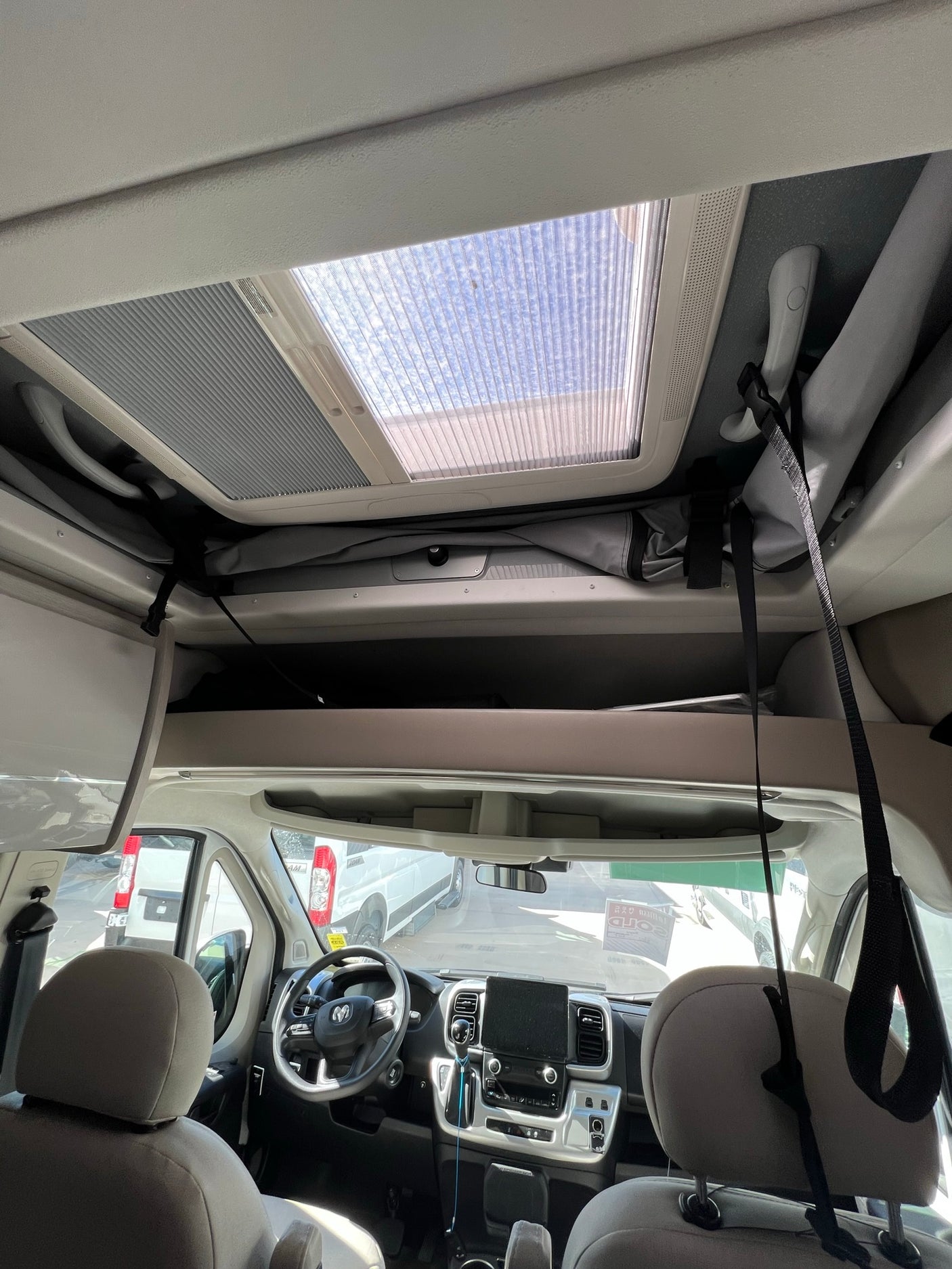 Inside an RV rental: view of the cab, overhead storage, and skylight from the living area. Ready for adventure!
