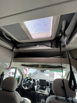 Inside an RV rental: view of the cab, overhead storage, and skylight from the living area. Ready for adventure!
