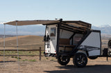 An off-road TigerMoth **RV rental** trailer, with its awning extended, offers adventure in a mountain setting.