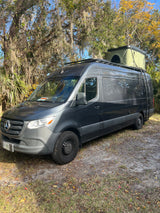 Dark gray Mercedes Sprinter camper van with rooftop tent. Ideal for RV rental adventures & camping trips.