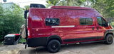 Explore in this custom red camper van, available for RV rental. Features a roof AC and rear cargo carrier with a Yeti cooler.
