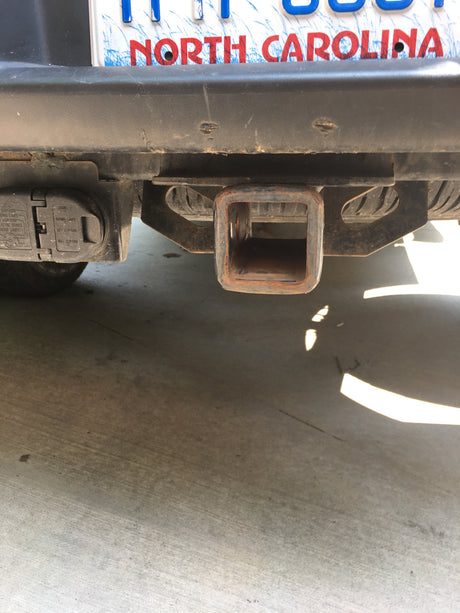 Rear of an RV rental or vehicle, showing its North Carolina license plate, trailer hitch receiver, and electrical connector for towing.