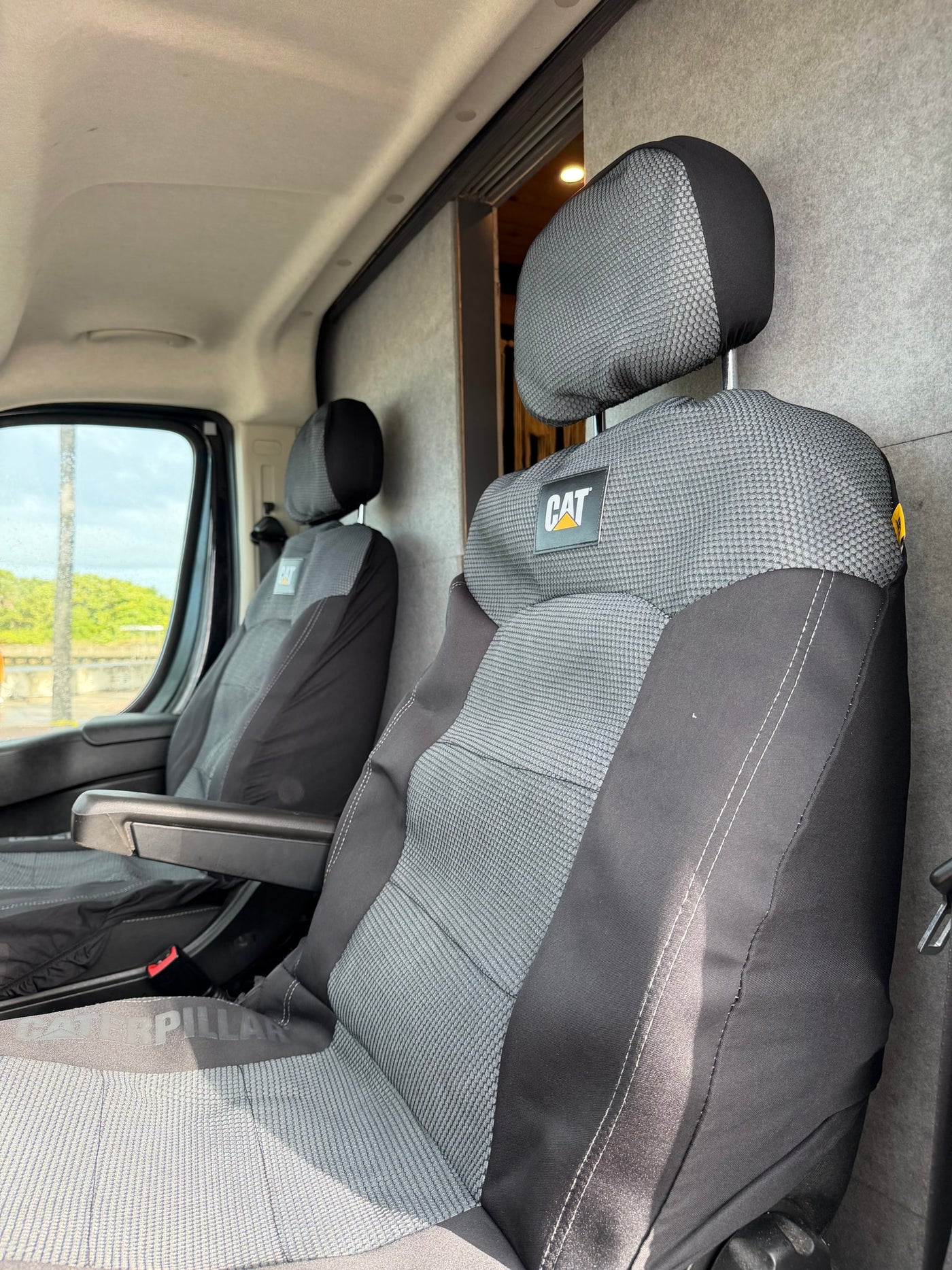  seen from the open back door with beach reflections.|Open rear doors of a black RV rental camper van reveal its modern interior cabinetry — photo 10