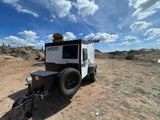 Ready for adventure: This white TigerMoth off-road RV rental camper is parked in a rugged, scenic landscape.