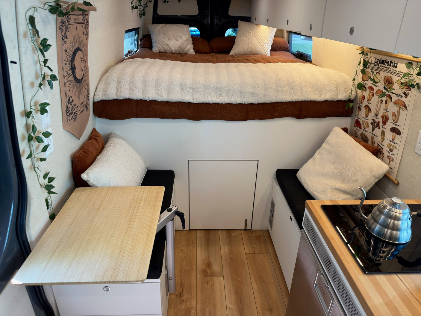 Cozy RV rental interior features a raised bed, dining area, and compact kitchen setup, ideal for adventurous travel.