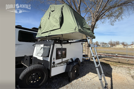 Explore with our TigerMoth rv rental! This compact trailer features a green rooftop tent & ladder for outdoor camping.