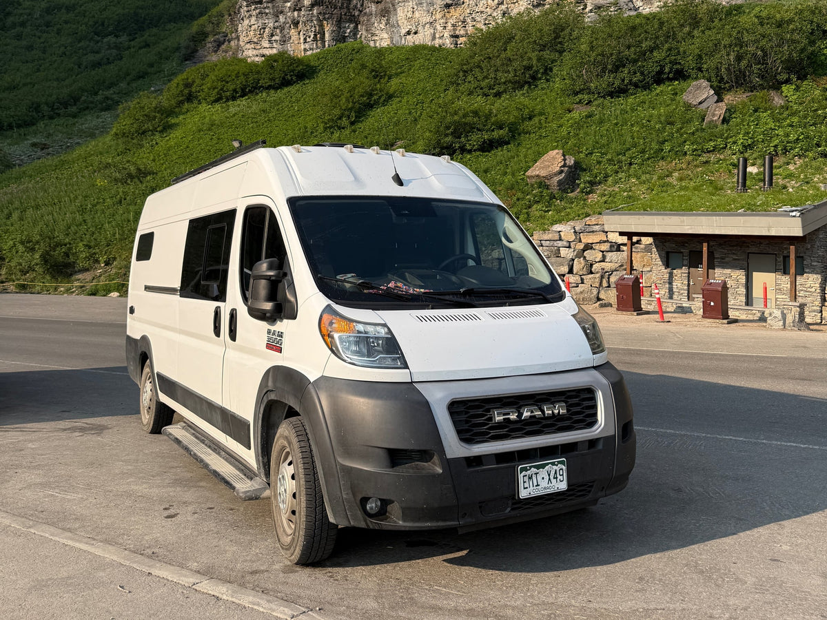  ready for adventure.|Happy couple and their RV rental in front of Yosemite's Half Dome at golden hour. Perfect national park adventure!|White Ram ProMaster rv rental parked near a scenic mountain with a stone park facility. Great for nature trips!|Serene mountain sunset from an RV rental. Person relaxing on a bed — photo 4