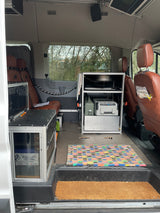 Custom camper van interior for RV rental: features kitchen, fridge, battery, seating, and overhead screen.