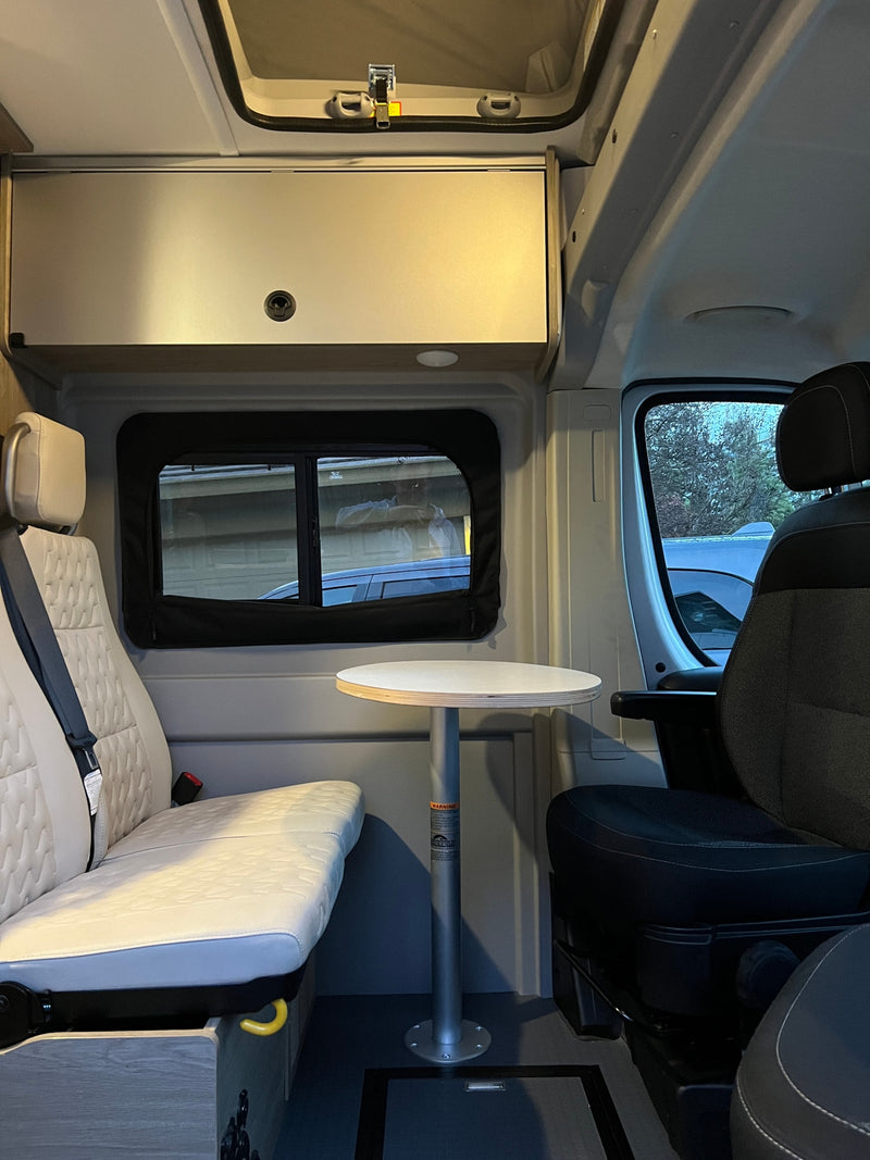 Inside a cozy **rv rental**: quilted bench seat, round table, and front passenger seat. Ideal for your next adventure. — photo 25