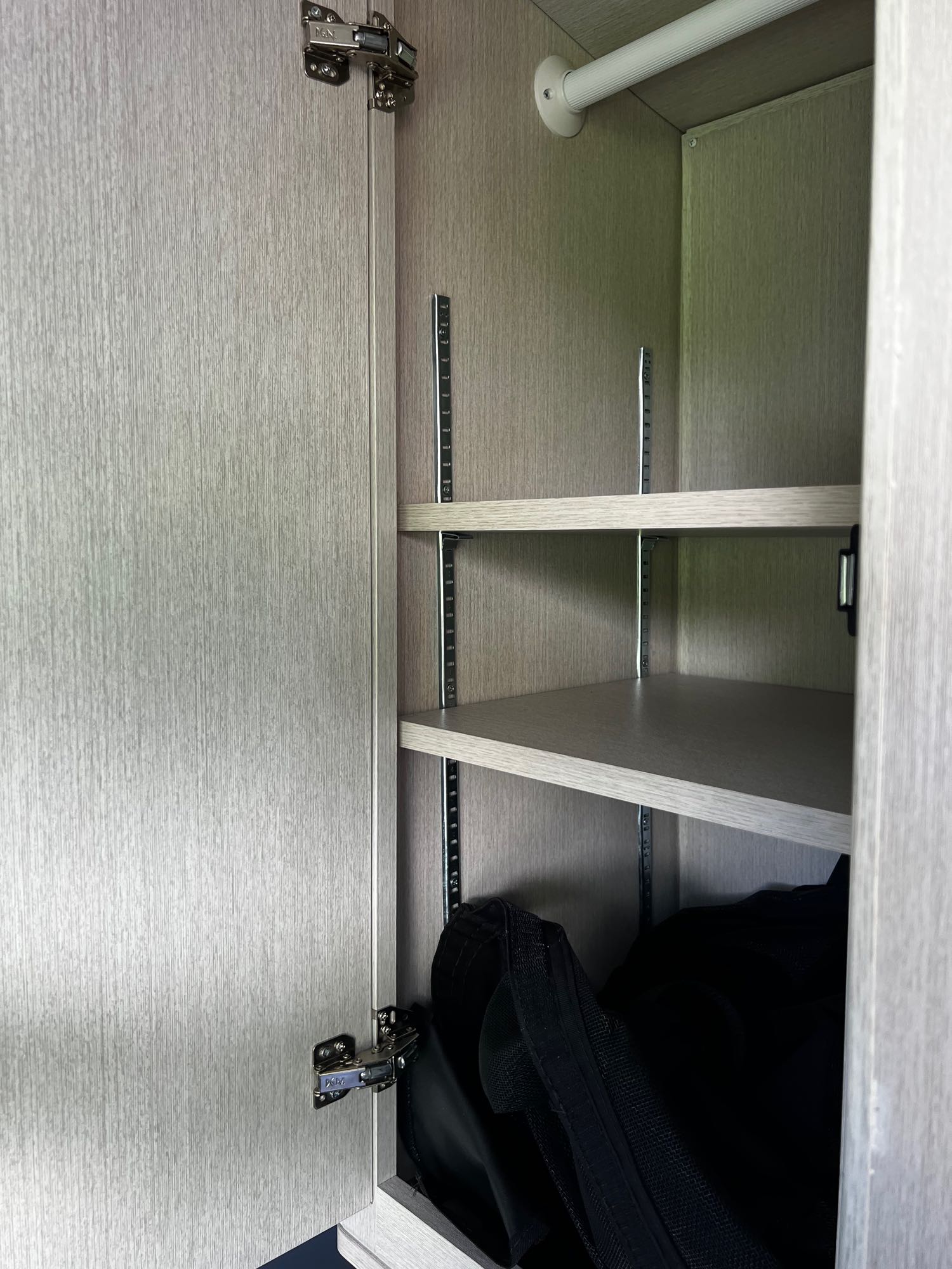RV rental features: Light-wood cabinet with adjustable shelving & hanging rod for efficient storage.