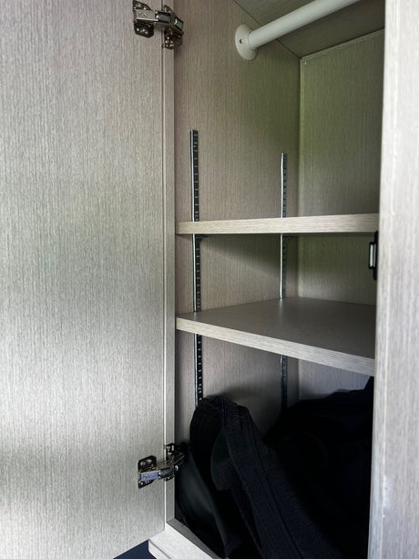 RV rental features: Light-wood cabinet with adjustable shelving & hanging rod for efficient storage.