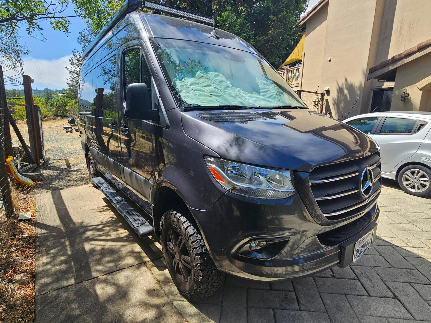 This gray Mercedes-Benz Sprinter rv rental is parked on a sunny driveway, ready for its next travel adventure.