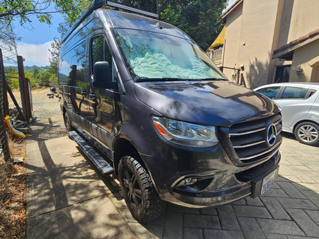 This gray Mercedes-Benz Sprinter rv rental is parked on a sunny driveway, ready for its next travel adventure.