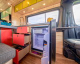 RV rental interior shows a bright kitchen with red & yellow cabinets, a stainless sink, and an open fridge.
