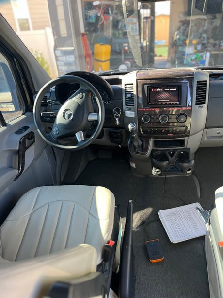 Detailed interior of an RV rental Mercedes-Benz Sprinter van, showing the cockpit, dashboard, and driver's seat.
