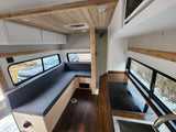 Spacious rv rental interior showing a kitchen, L-shaped seating, and shower stall, with wood and white accents.