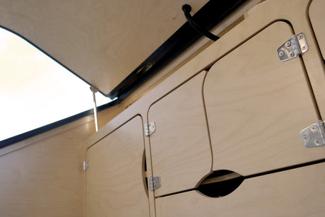 RV rental interior showcasing light plywood cabinetry and an open pop-top for ample storage.