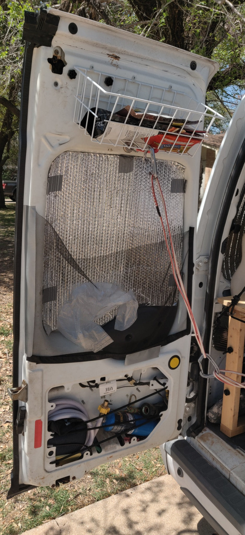 RV rental van door: DIY storage basket, reflective insulation, and lower storage for hoses & propane. — photo 17