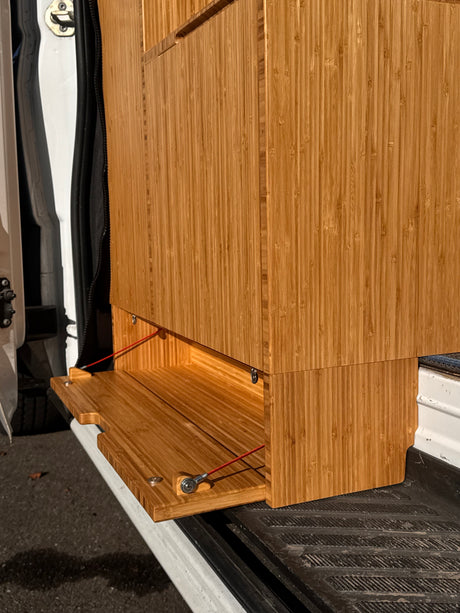 Bamboo cabinetry with a pull-out table inside an RV rental. Ideal for a campervan's versatile living space.