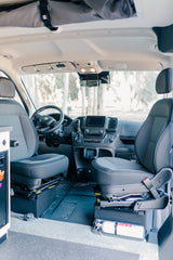 RV rental: Inside a modern camper van cockpit, showing driver/passenger seats, dashboard, and fire extinguisher.