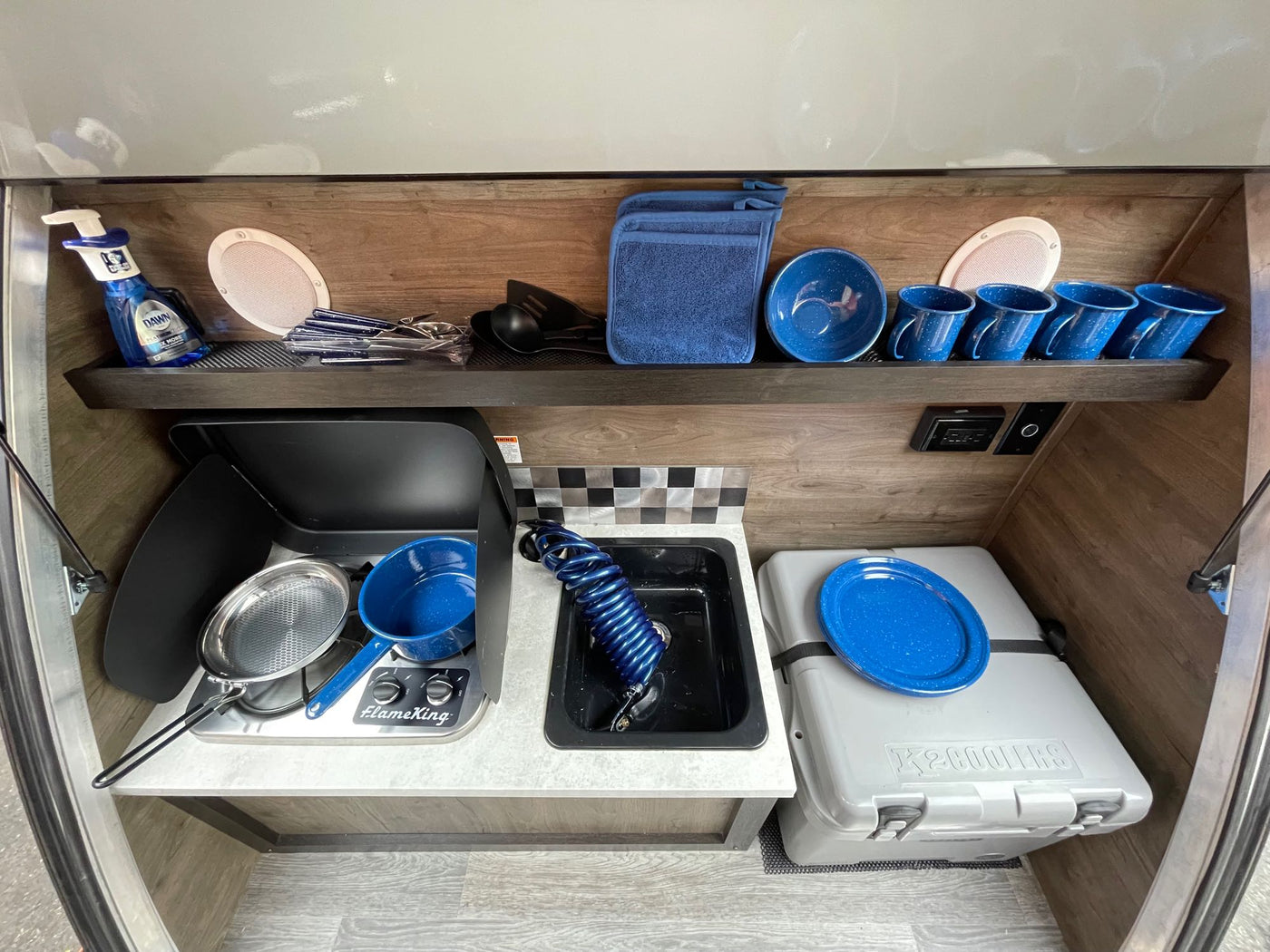  against majestic snow-capped mountains and bare trees.|This RV rental's compact kitchen offers essential camping amenities