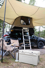 Car camping ready! This black Subaru Crosstrek with a rooftop tent, awning, chairs, and cooler offers a flexible RV rental alternative.