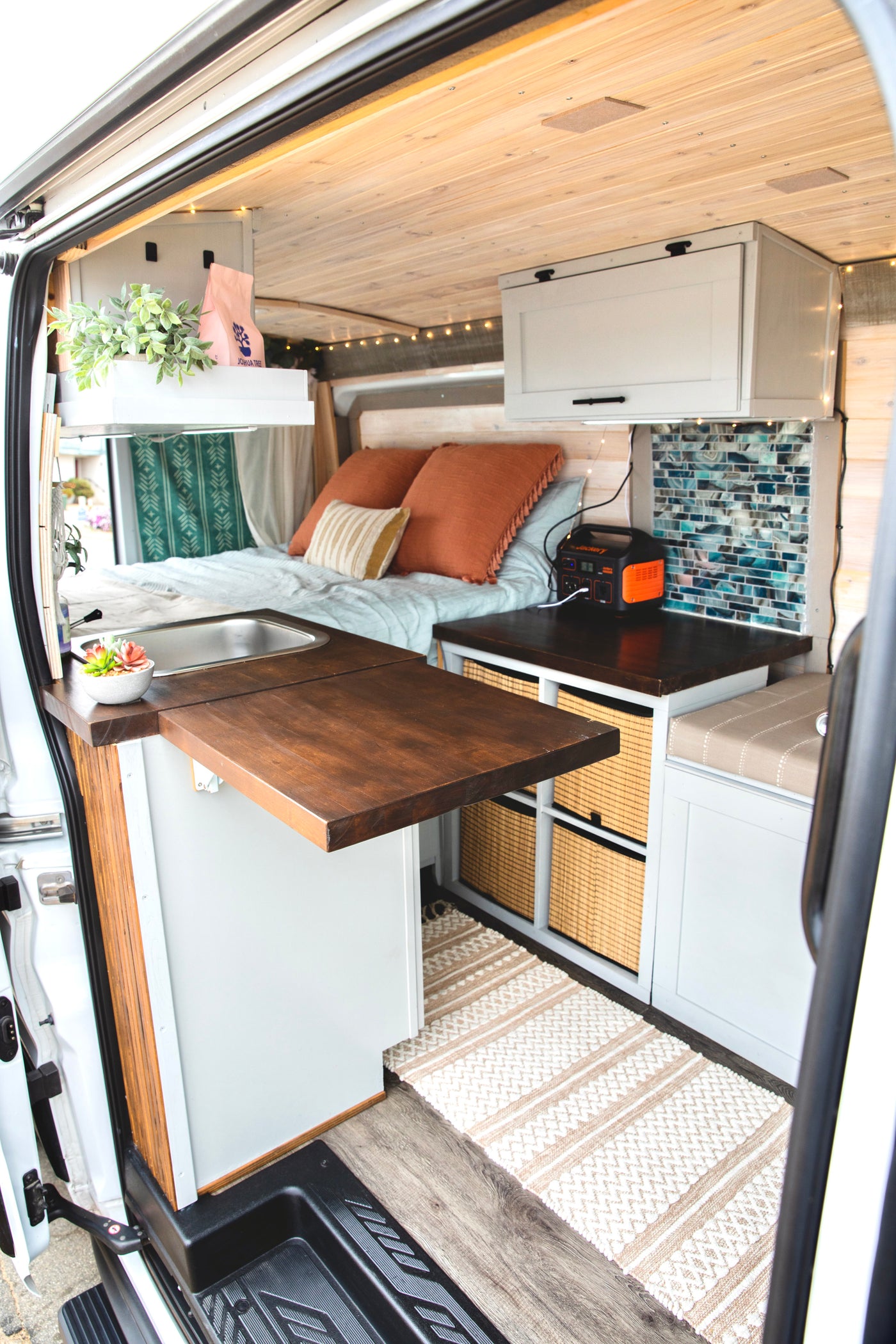 Explore custom living in this cozy rv rental camper van. Features a compact kitchen, comfy bed, and smart storage solutions. — photo 9
