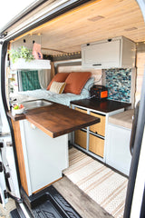 Explore custom living in this cozy rv rental camper van. Features a compact kitchen, comfy bed, and smart storage solutions.