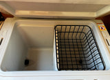 RV rental fridge interior: partitioned space with drain plug and wire storage basket for organized travel.